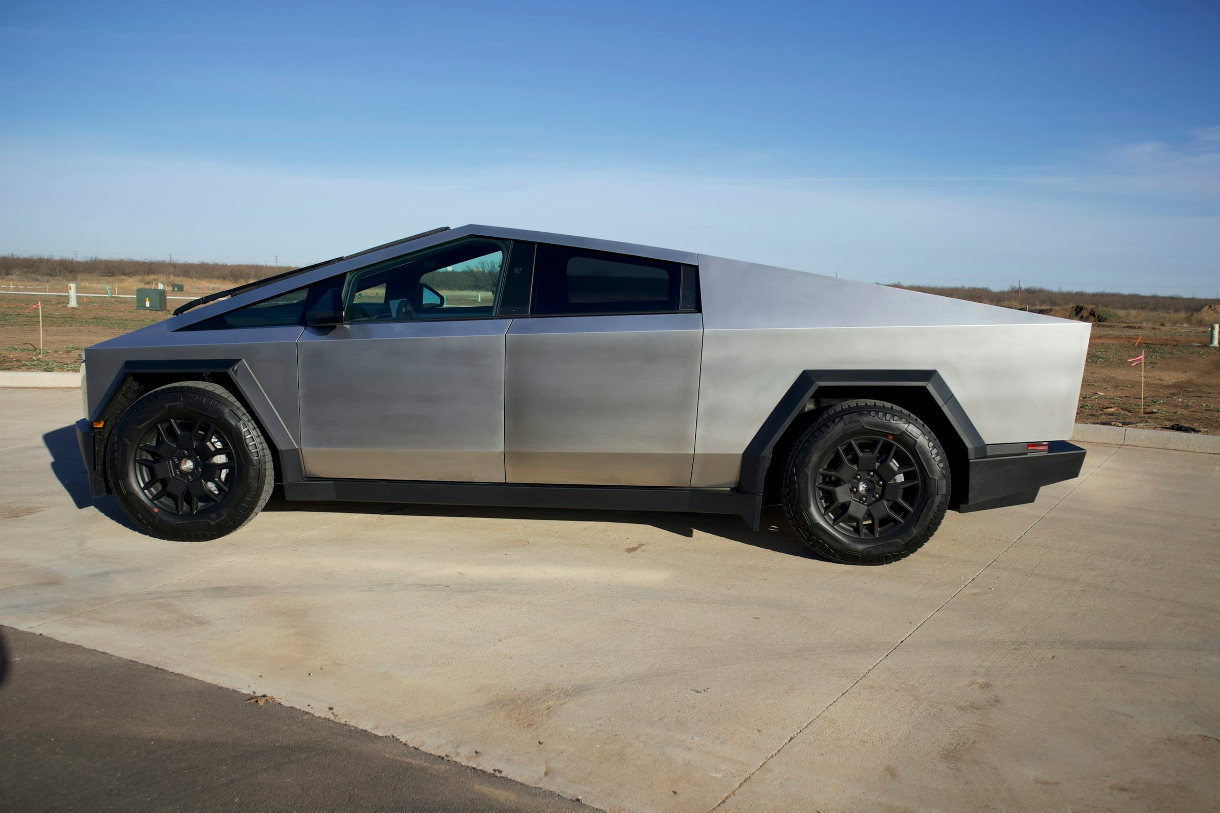 Stainless steel Tesla Cybertruck parked under a clear sky
