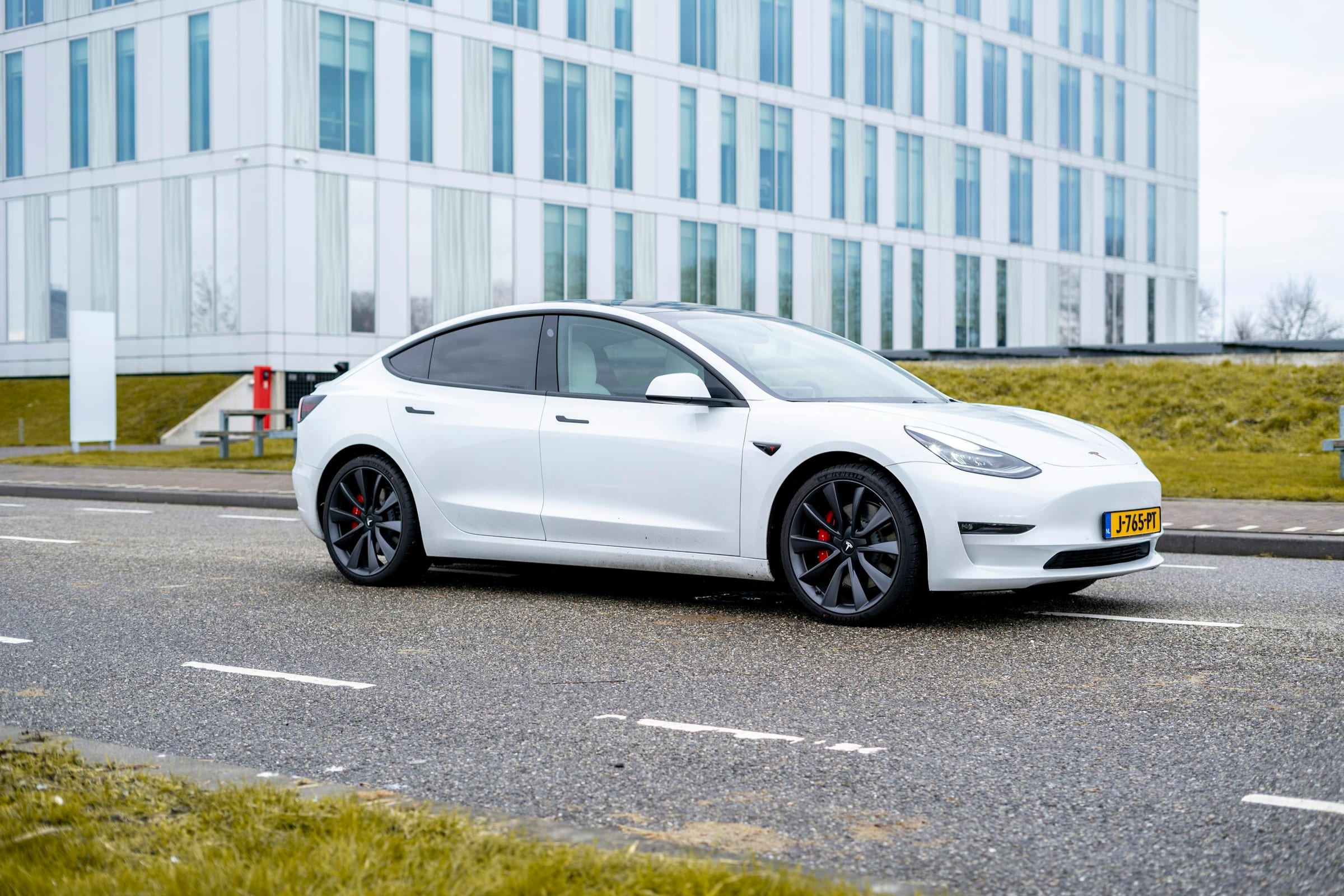 White Tesla Model 3 parked beside a modern building